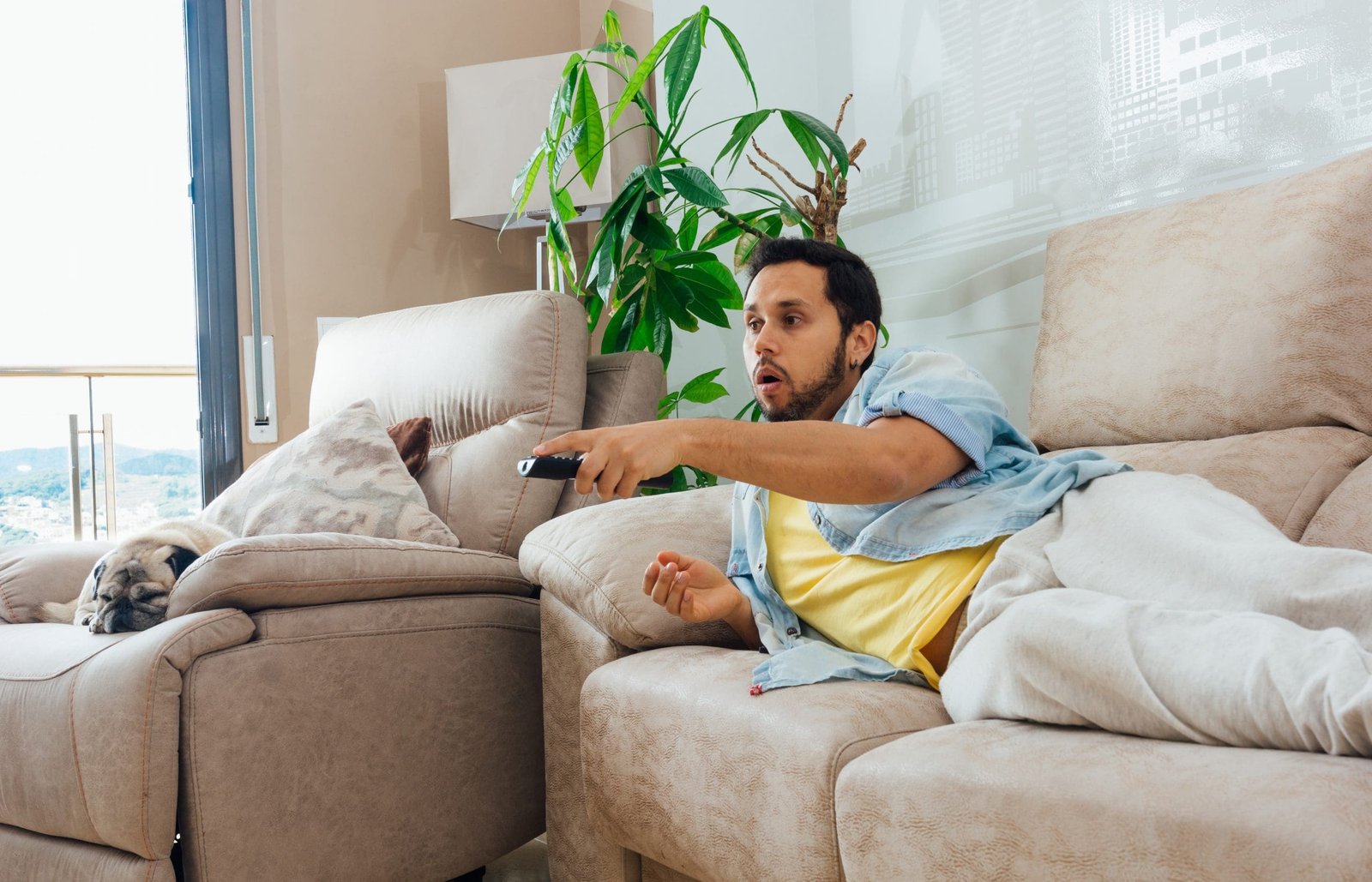 Photo of a handsome Hispanic man lying on a sofa and watching TV
